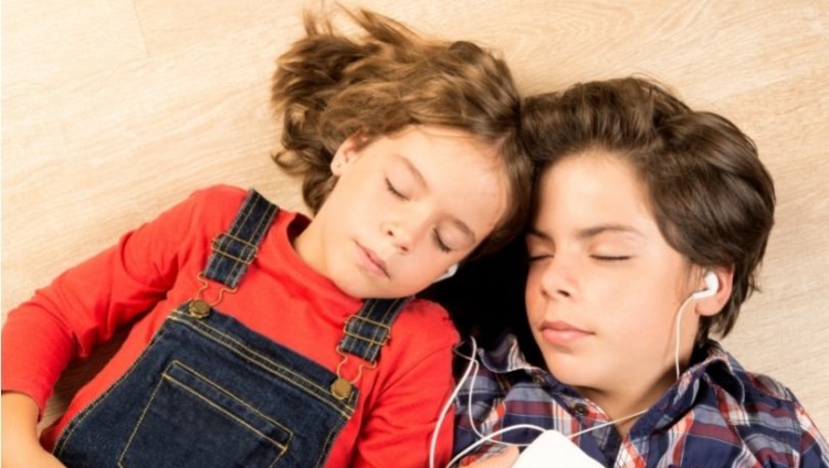 Kaksi lasta kuuntelee musiikkia kuulokkeista silmät kiinni