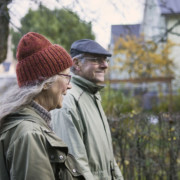 Vanhahko nainen ja mies syksyisellä kävelyllä puutaloalueella