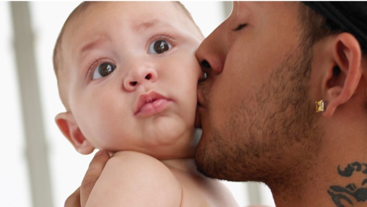 Nuori mies antaa vauvalle suukon poskelle