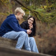Kuvassa kaksi nuorta juttelee ulkona puistossa. Kuvassa toinen nuori kuuntelee keskittyneesti, mitä toinen kertoo.