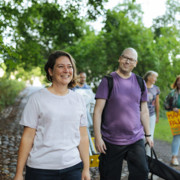 Iloinen ryhmä kävelee puistossa tapahtumatavaroita kantaen