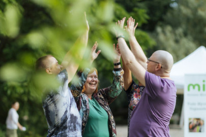 Neljän hengen ryhmä iloisia ihmisiä kohottaa kädet yhteen.