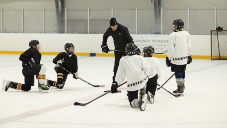 Nuorte jääkiekkoilijat kuuntelevat valmentajaansa
