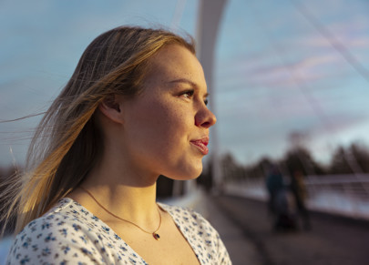 Lukioikäinen tyttö hymyilee ja katsoo oikealle auringonpaiste kasvoillaan.