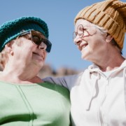 Kaksi eläkeikäistä naista vierekkäin katsovat toisiaan