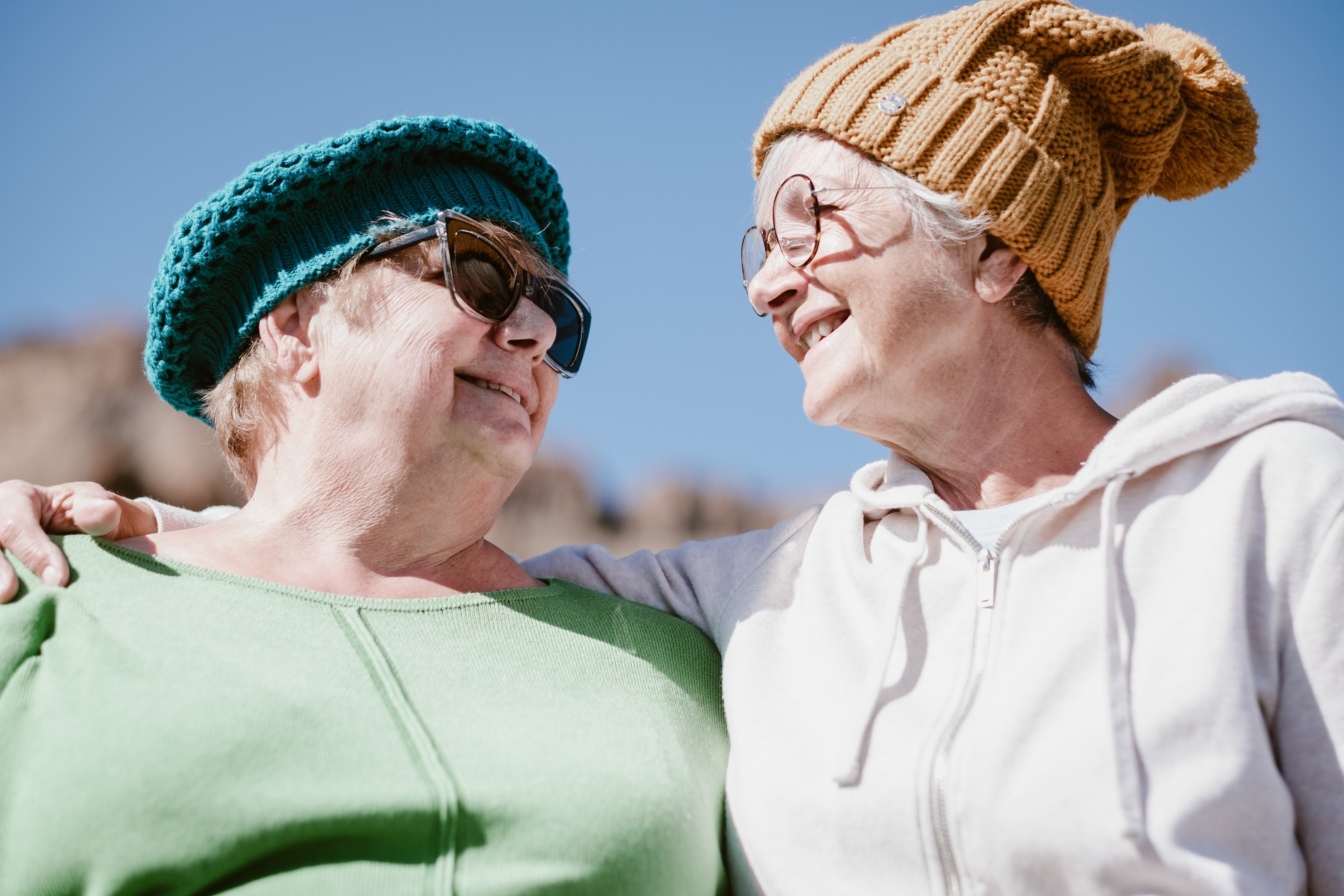 Kaksi eläkeikäistä naista vierekkäin katsovat toisiaan