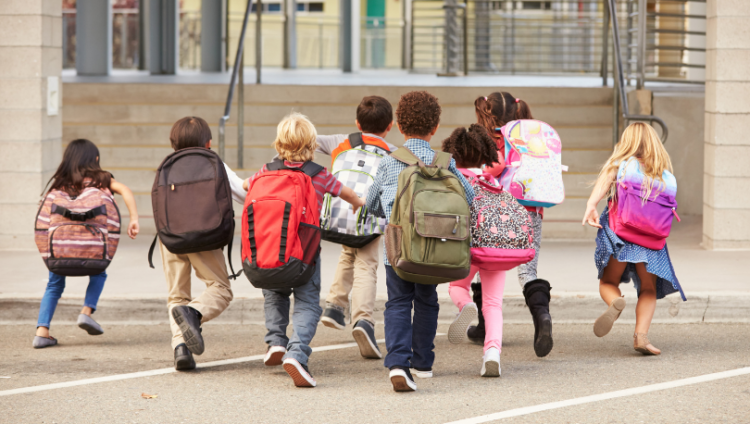 Eri näköisiä lapsia juoksemassa koulureput selässä