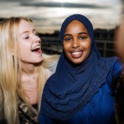 somalialaistautainen tyttö huivi päässä katsoo kameraan, vaalea tyttö halaa vieressä