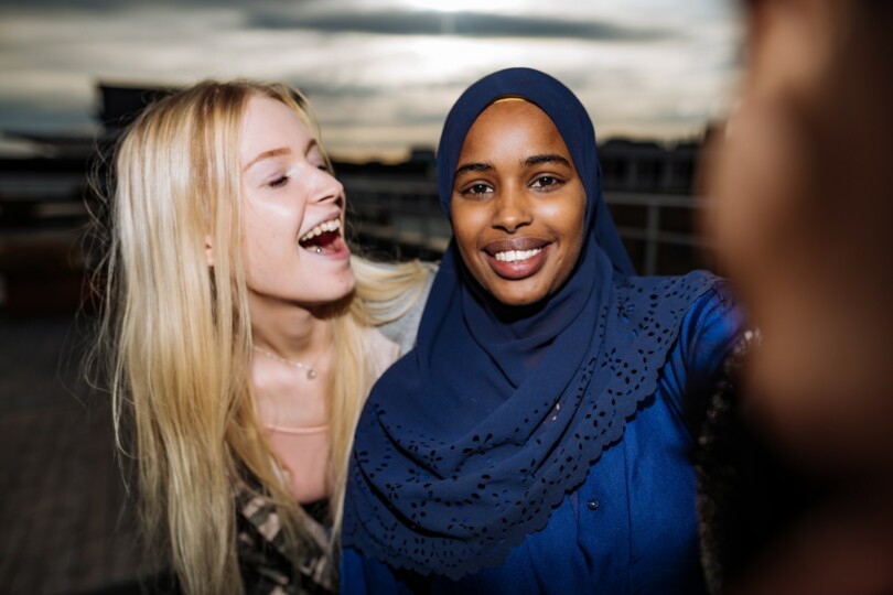 somalialaistautainen tyttö huivi päässä katsoo kameraan, vaalea tyttö halaa vieressä