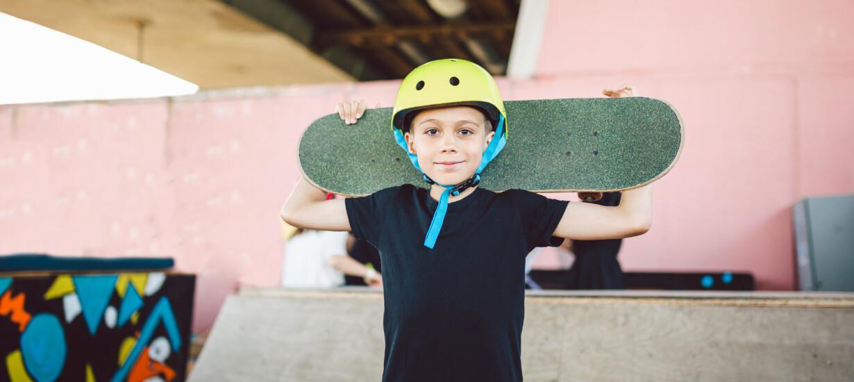 ung person med hjälm på huvudet och skateboard på axeln