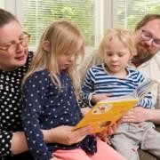 Mamma, pappa och två barn läser boken tillsammans.