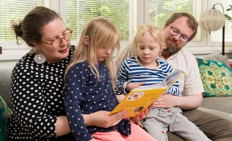 Mamma, pappa och två barn läser boken tillsammans.