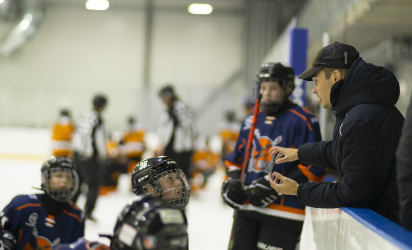 Tränaren talar till de unga ishockeyspelarna.