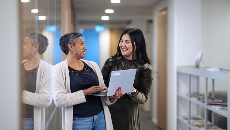 Kaksi henkilöä keskustelee toimiston käytävällä.