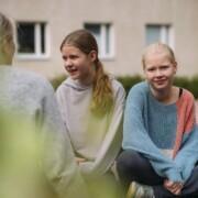 En vuxen kvinna samtalar med två flickor
