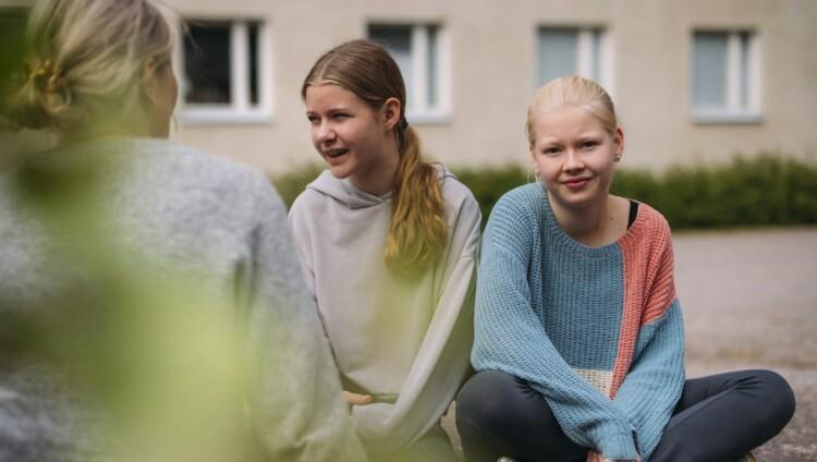 En vuxen kvinna samtalar med två flickor
