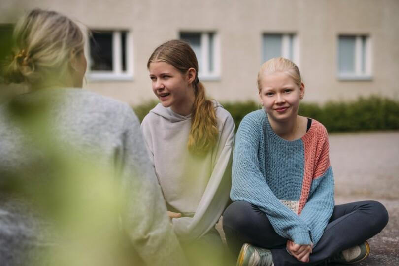 En vuxen kvinna samtalar med två flickor
