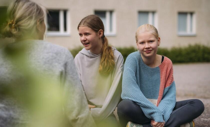 En vuxen kvinna samtalar med två flickor