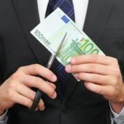 Pukumies leikkaa saksilla 100 euron seteliä