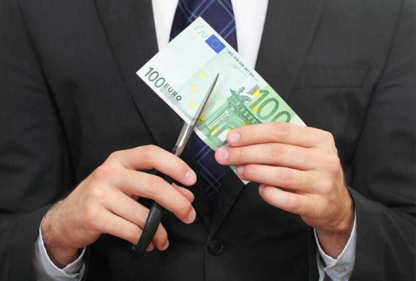 Pukumies leikkaa saksilla 100 euron seteliä