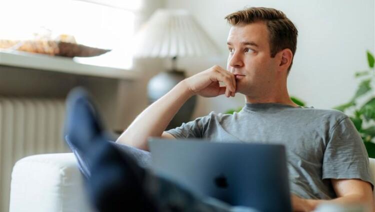 Mies tietokoneen ääressä katsoo kaukaisuuteen.