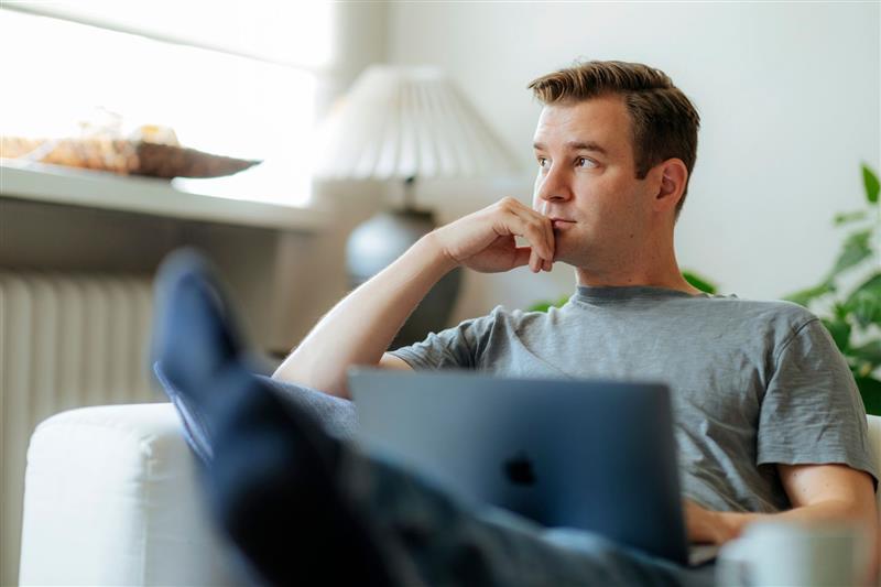 Mies tietokoneen ääressä katsoo kaukaisuuteen.