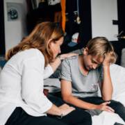 Nainen lohduttaa teini-ikäistä poikaa.