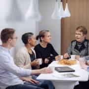 Työporukka juttelee kahvipöydän ääressä