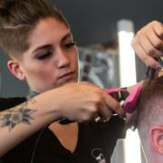 Kampaaja leikkaa asiakkaan hiuksia