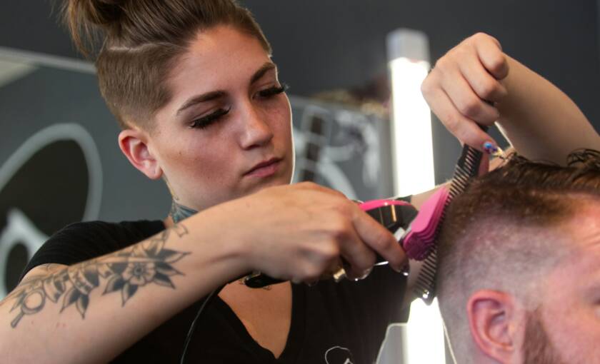 Kampaaja leikkaa asiakkaan hiuksia