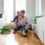 Vanhemmat ja lapsi leikkivät olohuoneessa