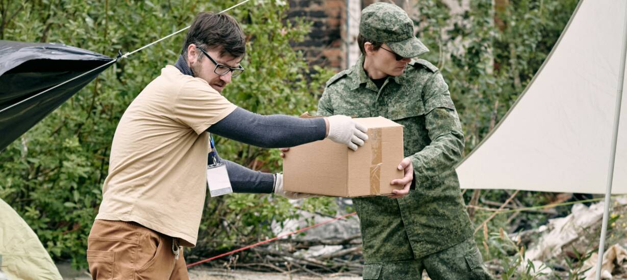 Mies ojentaa pahvilaatikkoa armeijapukuiselle miehelle