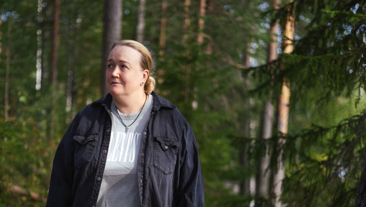 Nainen metsässä, katselee sivuun
