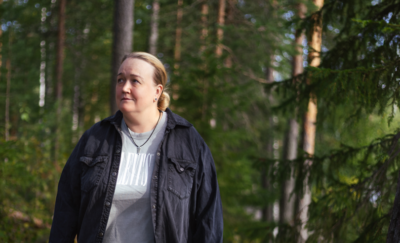 Nainen metsässä, katselee sivuun