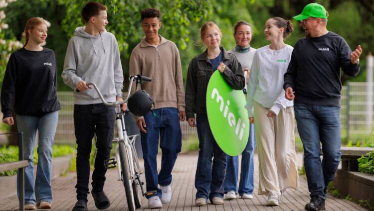 Ryhmä iloisia ihmisiä, kädessä iso MIELI-kyltti